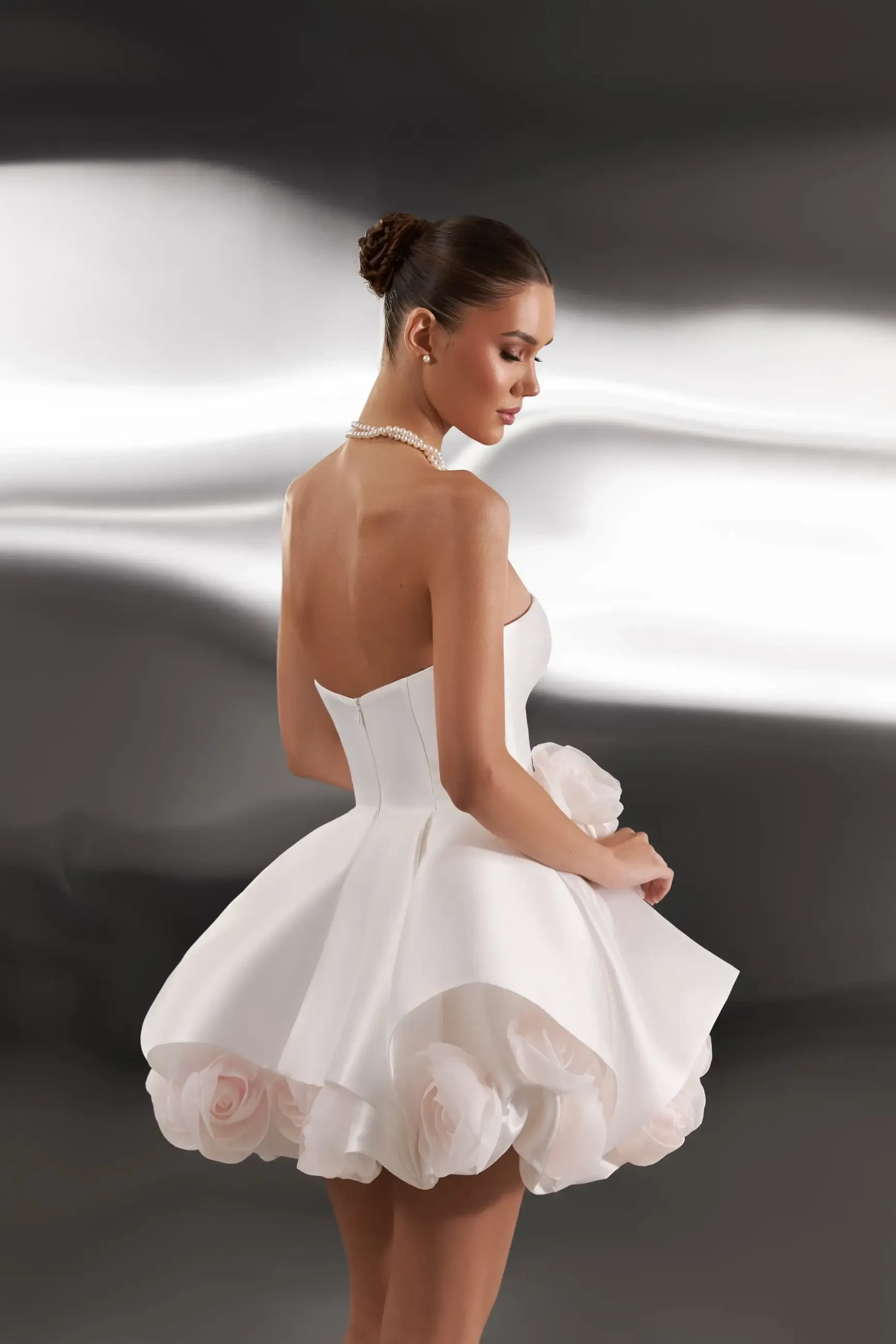 model is wearing a strapless mini wedding dress with floral accents 